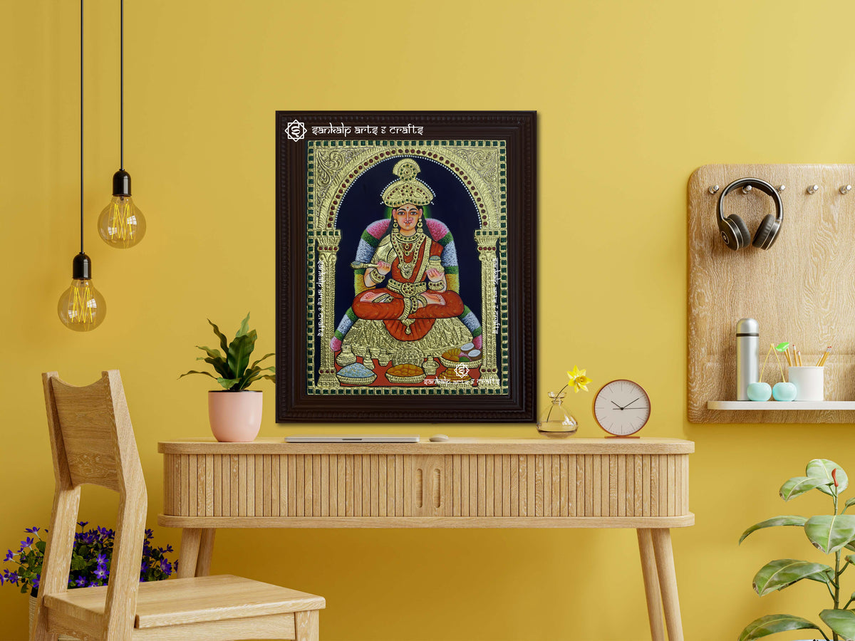 A framed Annapoorani Tanjore painting displayed as a wall hanging, radiating divine grace with vibrant hues, gold accents, and intricate artistic detailing.