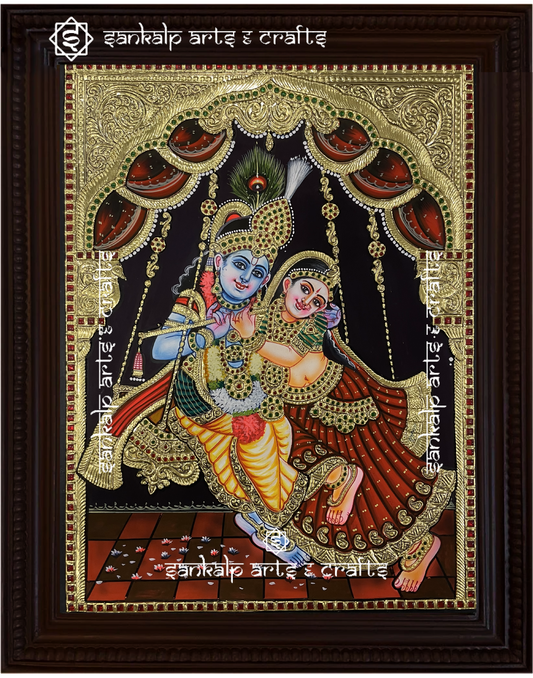 A beautifully framed Tanjore painting of Radha and Krishna on a swing (Jhula), handcrafted with intricate gold foil detailing. Perfect decor for homes in Chennai & Bangalore.